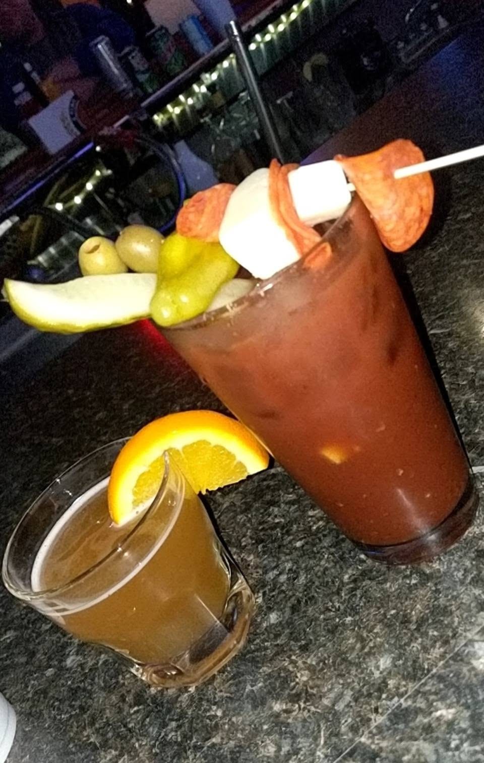 A loaded Bloody Mary with pickles, olives and meat sticks, and a beer chaser with an orange slice