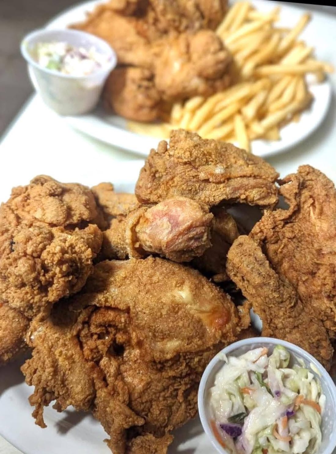 A plate of crispy fried chicken with fries and coleslaw