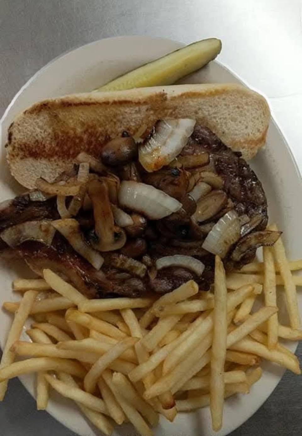 A prime rib sandwich with grilled onions and fries